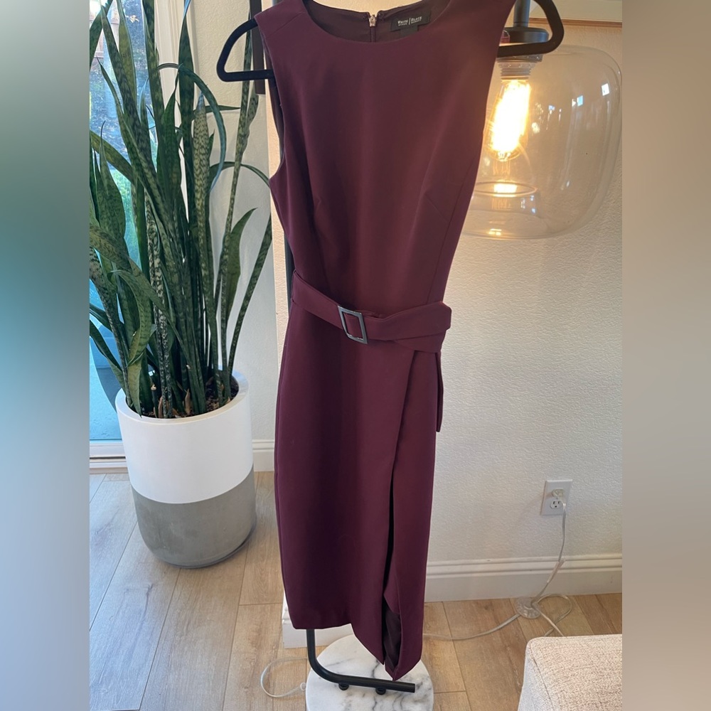 Sleeveless dress with belt and skirt has opening.